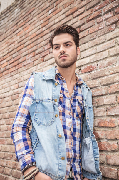 young casual man leaning on a brick wall - Photo, Image