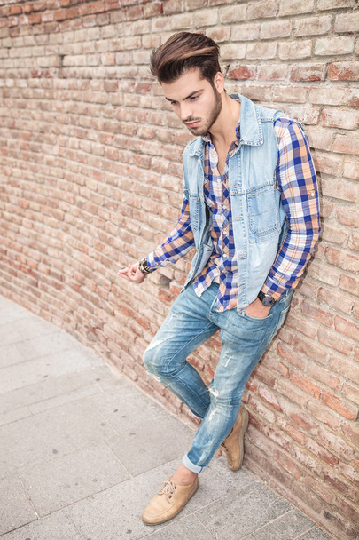 man leaning on brick wall looking down - Fotografie, Obrázek