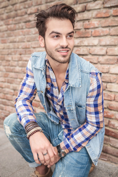 handsome man sitting near a brick wall - Фото, зображення