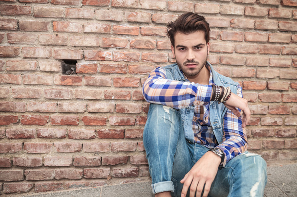 young man sitting near a brick wall, resting - Foto, immagini