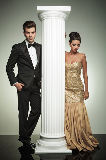 Atractiva pareja elegante posando cerca de la columna en el estudio
 - Foto, imagen
