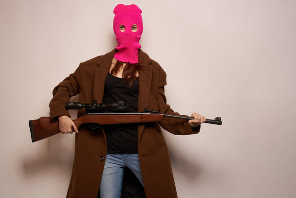 woman in pink mask with a gun in hand Lifestyle beige background - Photo, image