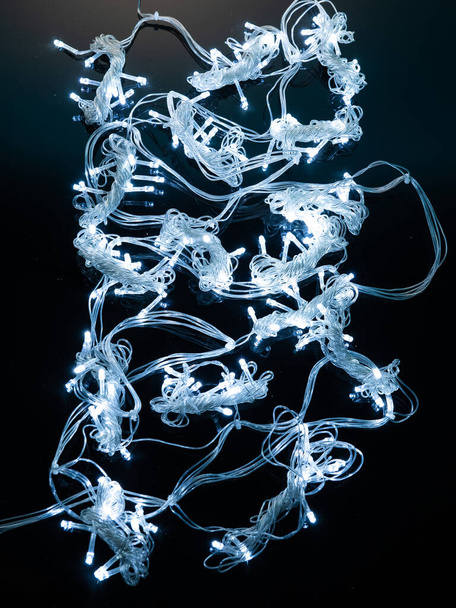 різнокольорова гірлянда з невеликими світлодіодними лампочками на темному фоні
 - Фото, зображення