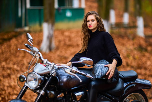Una hermosa mujer con el pelo largo en una motocicleta helicóptero en el paisaje de otoño. - Foto, Imagen