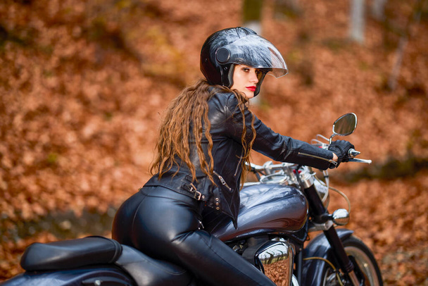 Uma bela mulher com cabelos longos em uma motocicleta helicóptero na paisagem de outono. - Foto, Imagem