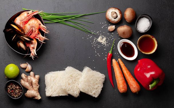 Ingredients for wok cooking with stir fried noodles, shrimps and vegetables on stone background. Top view flat lay with copy space - Photo, Image
