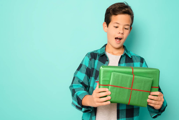 Happy kid boy holding many present and gift boxes isolated over green background. - Foto, Imagem