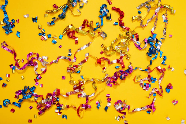 Colorful bright confetti and streamers on yellow background, top view. Copy space for text. Holiday mood, Christmas, New year, birthday or funny party. - Valokuva, kuva