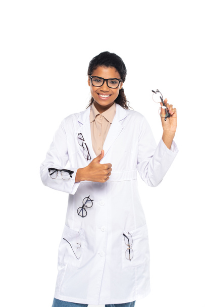 Positiivinen afrikkalainen amerikkalainen lääkäri, jolla on silmälasit valkoisessa takissa ja joka näyttää valkoiselle eristettyä peukaloelettä  - Valokuva, kuva