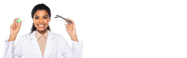 Χαρούμενος αφροαμερικανός γιατρός που κρατά τους οπτικούς φακούς και τα γυαλιά που απομονώνονται στο λευκό με το διάστημα αντιγράφων, λάβαρο  - Φωτογραφία, εικόνα