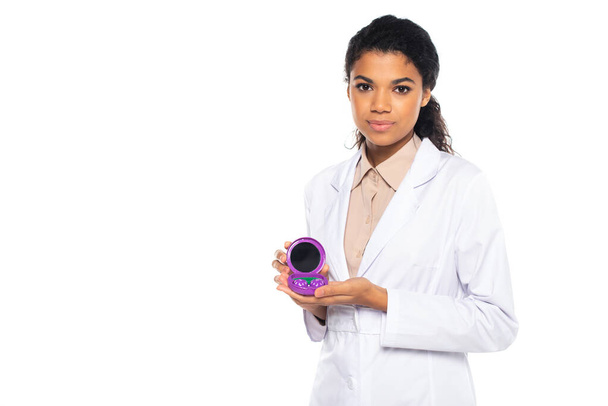 Young african american oculist holding container with contact lenses isolated on white  - Foto, afbeelding