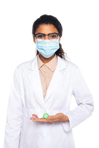 Afrikai-amerikai szemész orvosi maszkban és szemüvegben, kontaktlencsét tartva, fehér alapon izolálva.  - Fotó, kép