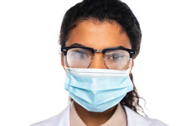 Médico afro-americano em máscara médica e óculos embaçados isolados em branco  - Foto, Imagem