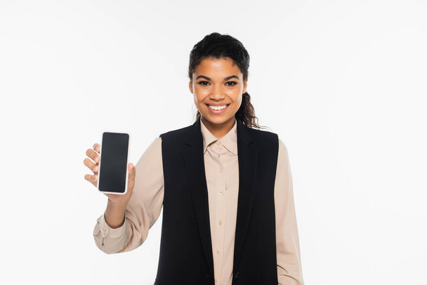 Positive african american businesswoman holding smartphone with blank screen isolated on white  - Fotoğraf, Görsel