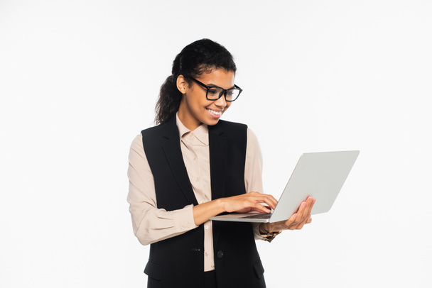 Souriante femme d'affaires afro-américaine utilisant un ordinateur portable isolé sur blanc  - Photo, image