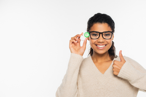 Mujer afroamericana sonriente en gafas con lentes de contacto y gestos aislados en blanco - Foto, imagen