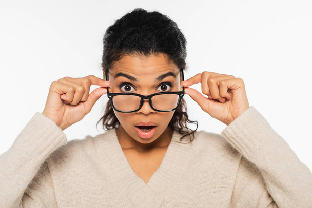 Shocked african american woman holding eyeglasses isolated on white - 写真・画像