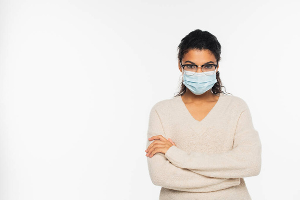 African american woman in eyeglasses and medical mask standing with crossed arms isolated on white - Foto, Imagem