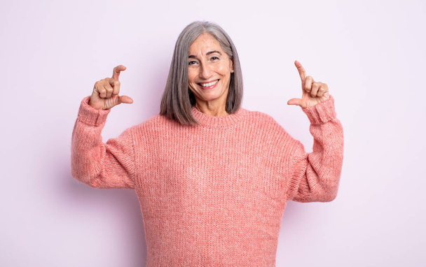 senior pretty woman framing or outlining own smile with both hands, looking positive and happy, wellness concept - Foto, Bild