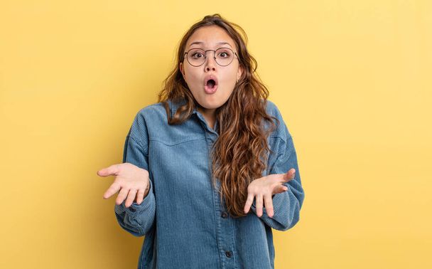 hispanic pretty woman feeling extremely shocked and surprised, anxious and panicking, with a stressed and horrified look - 写真・画像