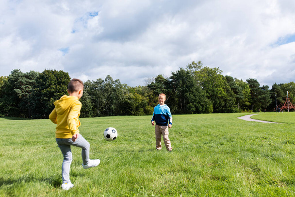 happy little boys with ball playing soccer at park - Photo, image