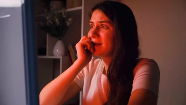 Una mujer ve una película de terror en la oscuridad, mordiéndose las uñas de la experiencia - Metraje, vídeo