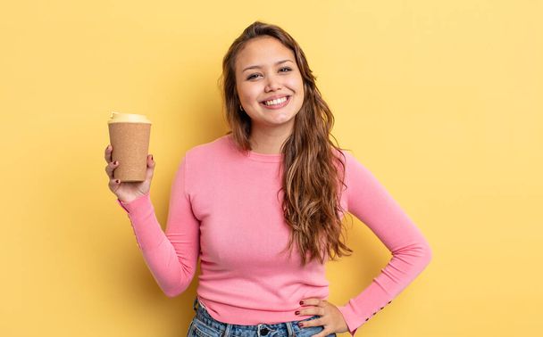 hispánská hezká žena se šťastně usmívá s rukou na boku a sebevědomě. odnést kávu koncept - Fotografie, Obrázek