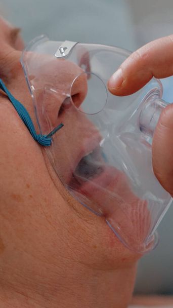 Arzt setzt kranken Patienten Sauerstoffmaske auf - Foto, Bild