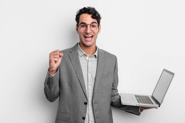 hispanic handsome man feeling shocked,laughing and celebrating success. business and laptop concept - Photo, image