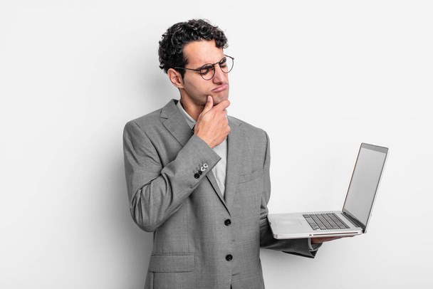 hispanic handsome man thinking, feeling doubtful and confused. business and laptop concept - Fotoğraf, Görsel