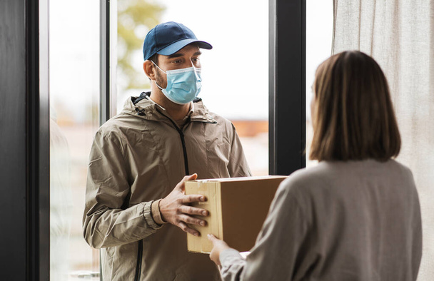 delivery man in mask giving parcel box to customer - Zdjęcie, obraz