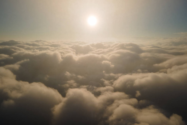 Vista aérea desde la ventana del avión a gran altitud de densas nubes de cúmulos hinchados que se forman antes de la tormenta de lluvia en la noche - Foto, Imagen