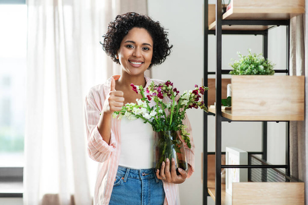 smiling woman holding flowers in vase at home - Foto, Imagen