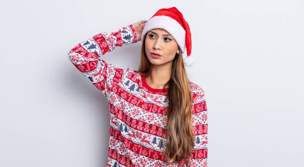 asiatic pretty woman feeling puzzled and confused, scratching head. christmas concept - Фото, изображение