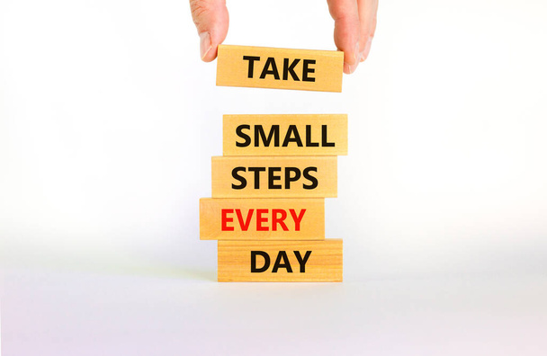 Take small steps every day symbol. Wooden blocks with words Take small steps every day. Beautiful white background, copy space. Businessman hand. Business, step every day concept. - Фото, изображение