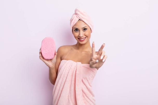 asiatic pretty woman smiling and looking happy, gesturing victory or peace. bathrobe and sponge concept - Valokuva, kuva