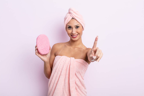 asiatic pretty woman smiling proudly and confidently making number one. bathrobe and sponge concept - Valokuva, kuva