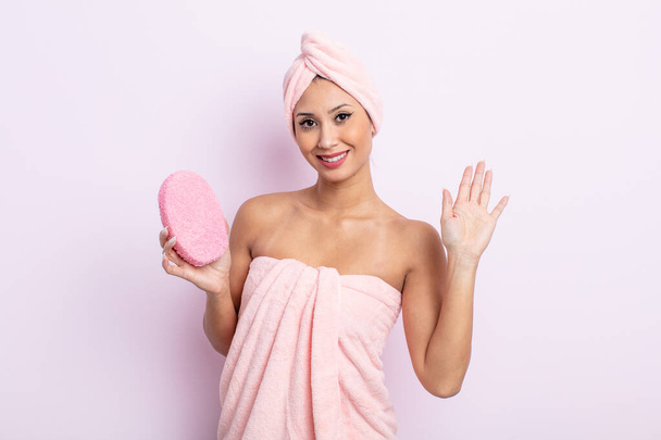 asiatic pretty woman smiling happily, waving hand, welcoming and greeting you. bathrobe and sponge concept - Fotografie, Obrázek