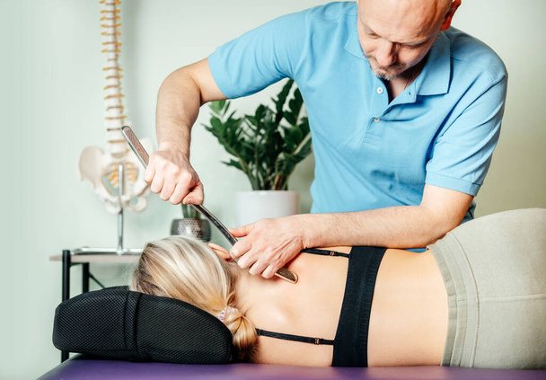 Chiropractor performing myofascial release techniques with IASTM tool for the Rhomboids - Foto, Imagen
