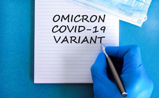 New covid-19 omicron variant strain symbol. Hand in blue glove with white note. Concept words Omicron covid-19 variant. Metalic pen. Medical and COVID-19 omicron variant strain concept. Copy space. - Foto, Imagen