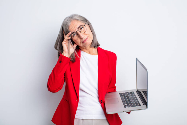 senior pretty woman feeling bored, frustrated and sleepy after a tiresome. business and laptop concept - Photo, image