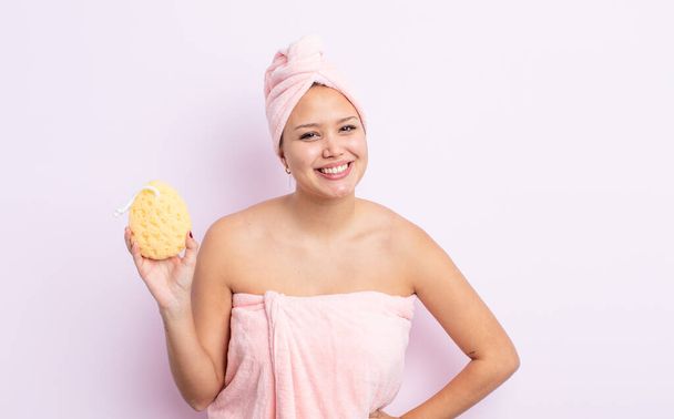 hispanic pretty woman smiling happily with a hand on hip and confident. bathrobe and sponge concept - Fotó, kép