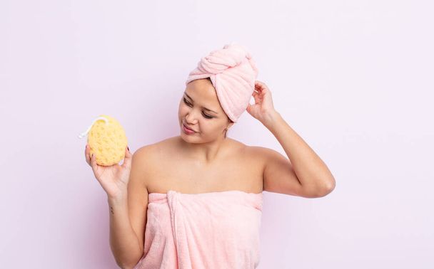 hispanic pretty woman smiling happily and daydreaming or doubting. bathrobe and sponge concept - 写真・画像