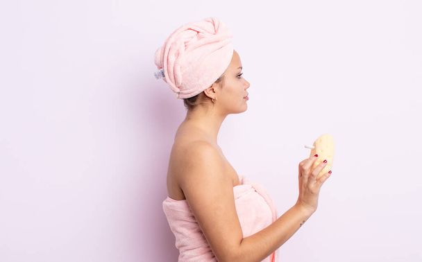 hispanic pretty woman on profile view thinking, imagining or daydreaming. bathrobe and sponge concept - 写真・画像