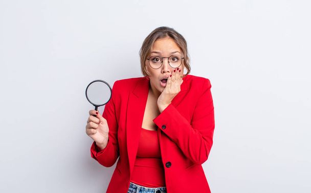 hispanic pretty woman feeling shocked and scared. magnifying glass concept - Photo, Image
