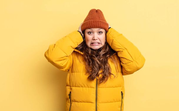 hispanic pretty woman feeling stressed, anxious or scared, with hands on head. winter clothes - Fotoğraf, Görsel
