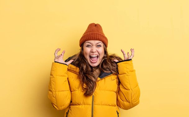 hispanic pretty woman screaming with hands up in the air. winter clothes - Photo, Image