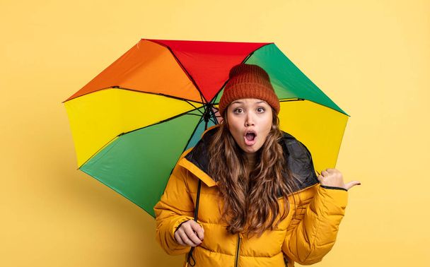 hispanic pretty woman looking astonished in disbelief. umbrella concept - Foto, Imagem