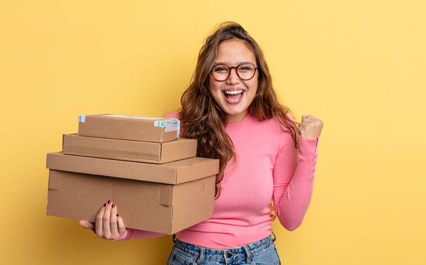 hispanic pretty woman feeling shocked,laughing and celebrating success. storage concept - Foto, Imagen