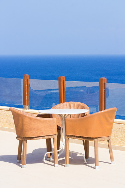 stół i krzesła na tarasie z widokiem na morze - Zdjęcie, obraz